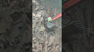 A worker on the bucket of a crawler excavator pulls something out of a rock with the bucket [upl. by Getter860]